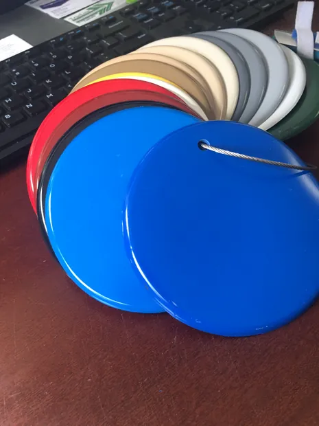 A stack of round solid-color coating samples in blue, red, yellow, tan, white and gray