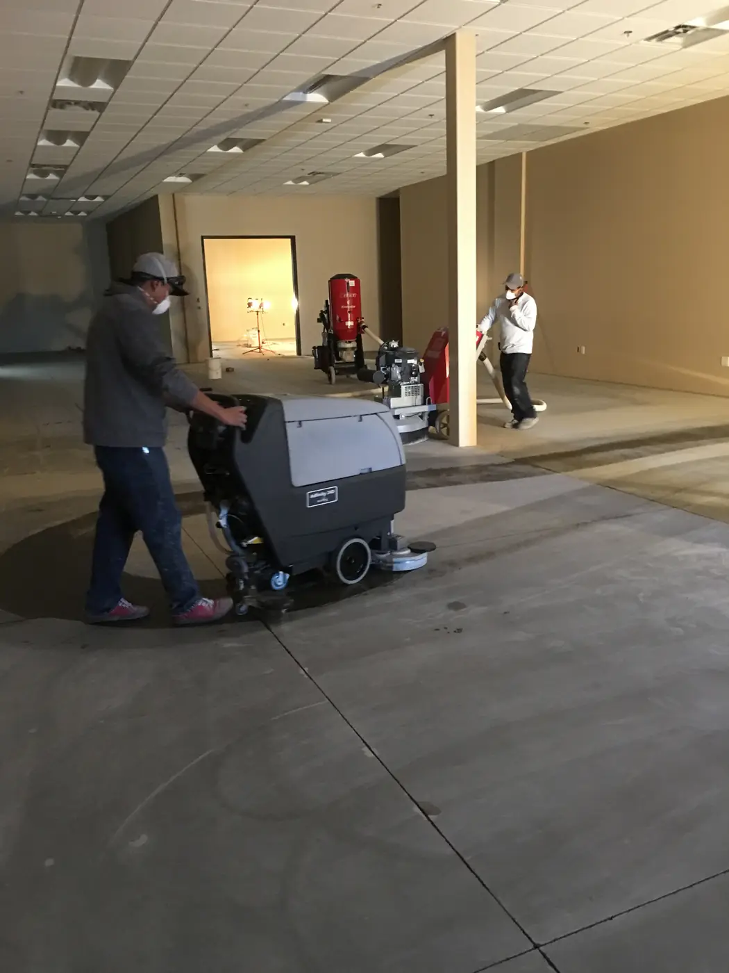 Crew running a floor machine to strip coating from a commercial room