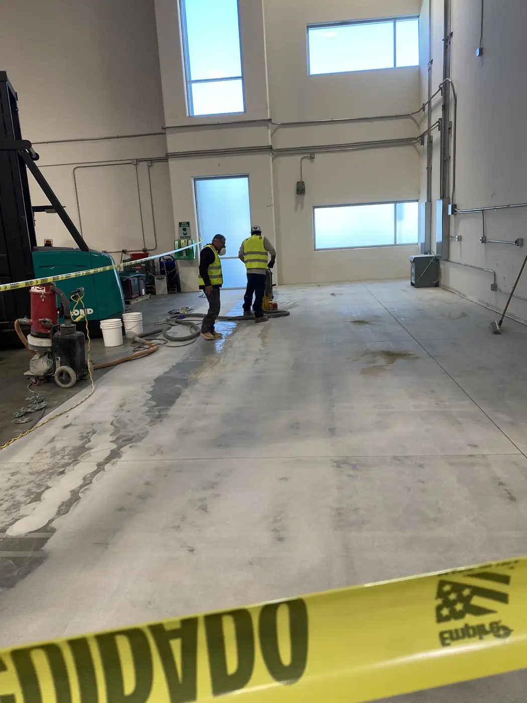 Crew and grinding equipment working across a warehouse slab during a coating removal