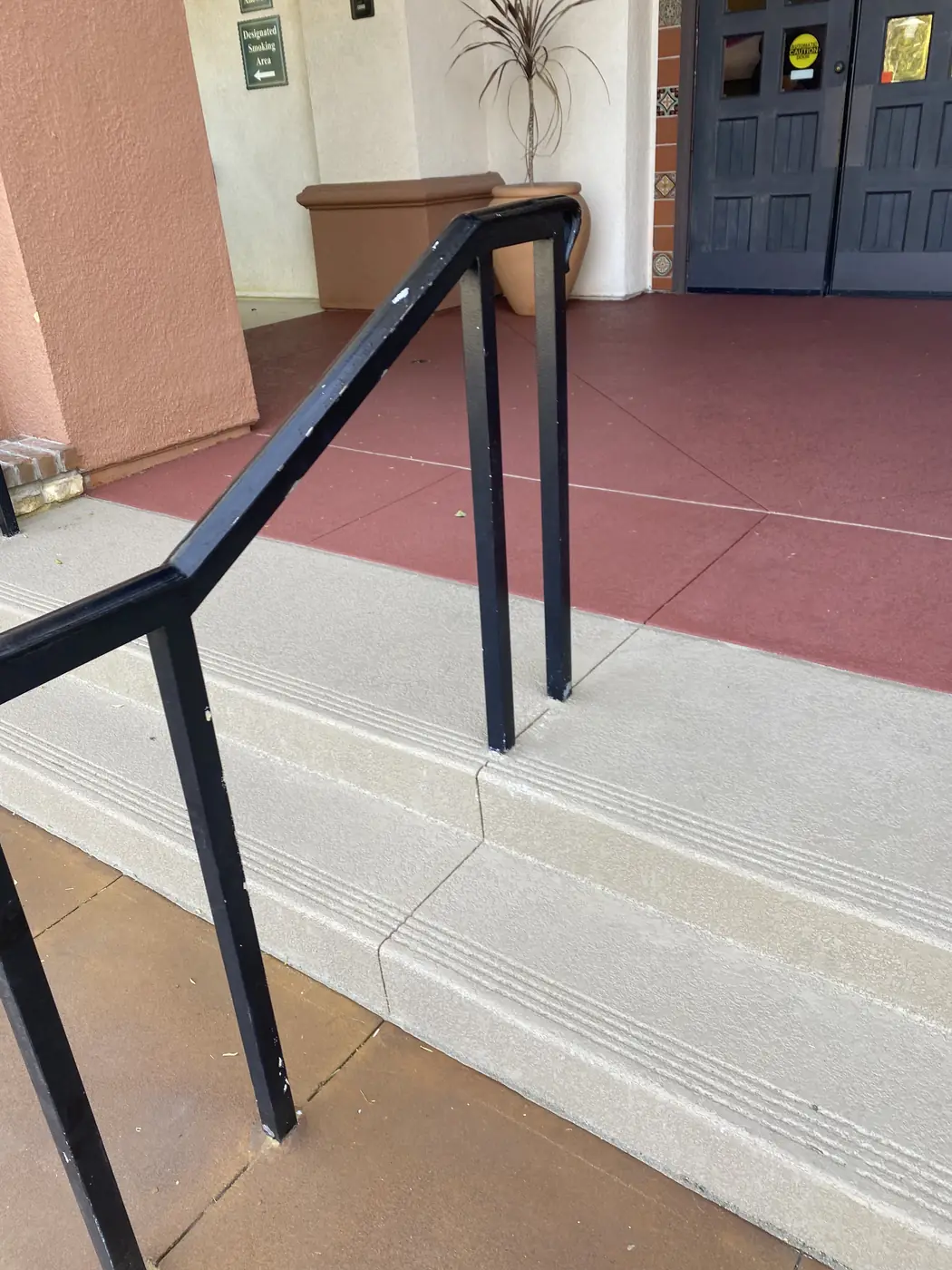 Resurfaced entry steps with a black handrail and a red bordered landing