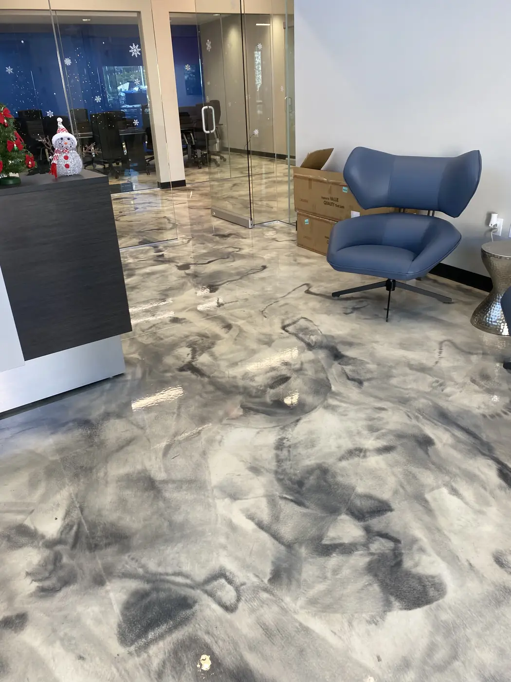 Marbled gray metallic epoxy floor in an office lounge with a blue armchair