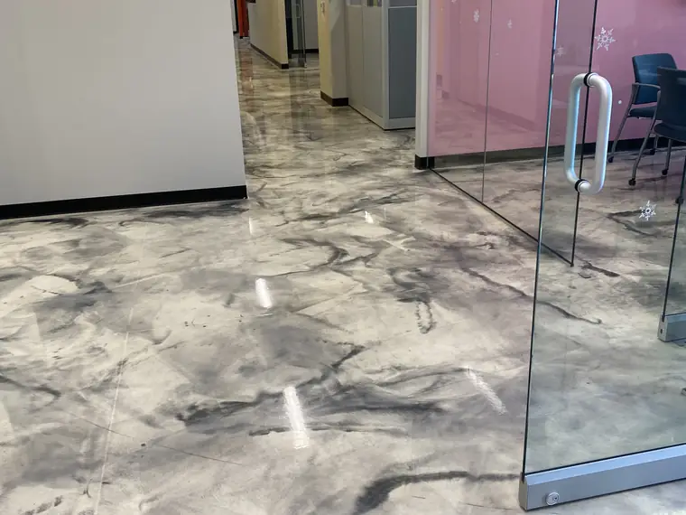 Gray and white metallic epoxy floor running down an office corridor past frosted glass