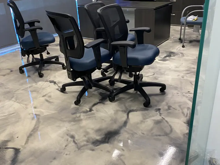 Office chairs standing on a swirled gray and white metallic epoxy floor