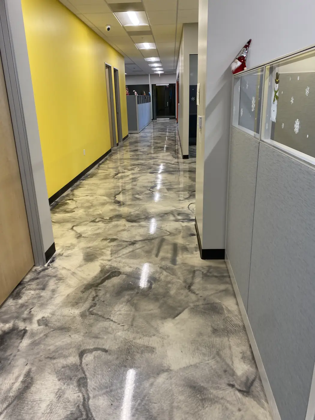 Metallic epoxy corridor between a yellow wall and office cubicles