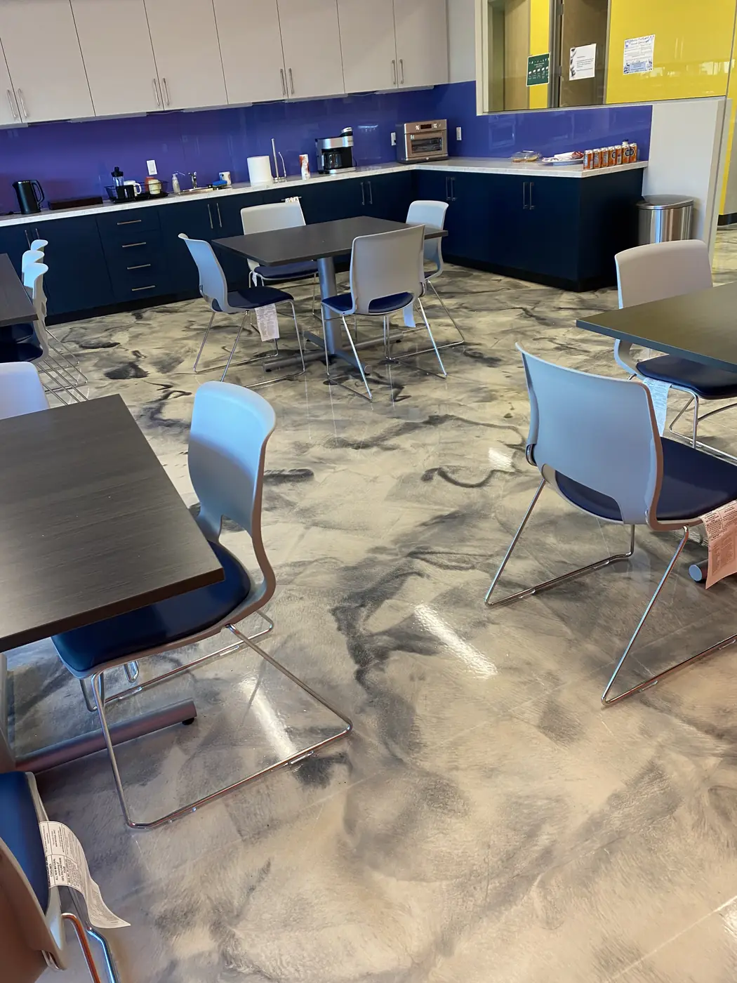 Office break room with navy cabinets standing on a marbled metallic epoxy floor