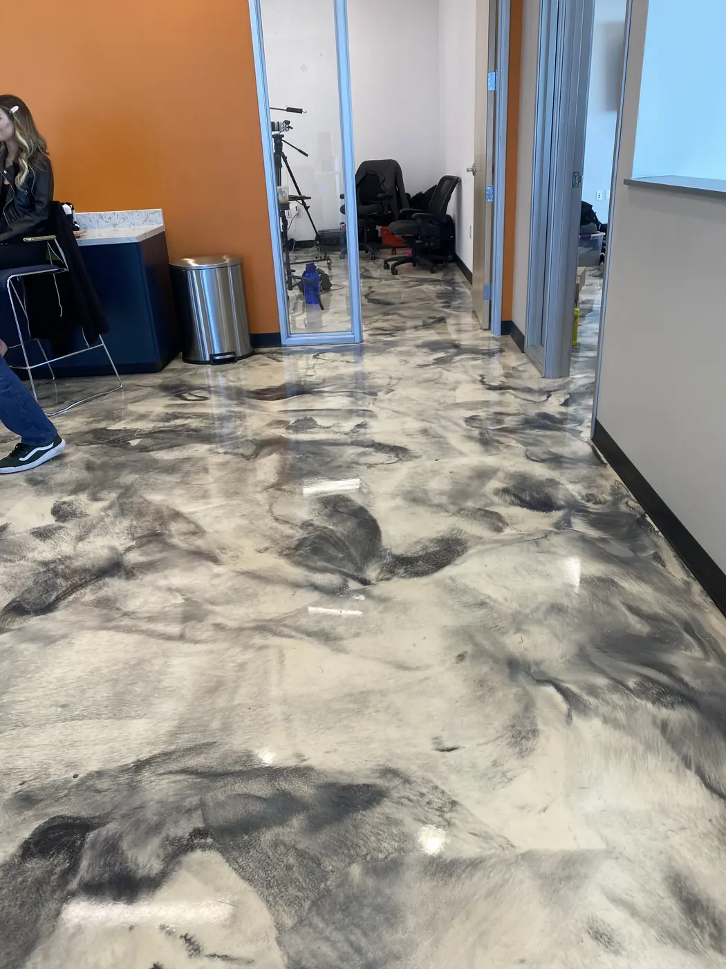 Metallic epoxy floor beside an orange accent wall in an office reception
