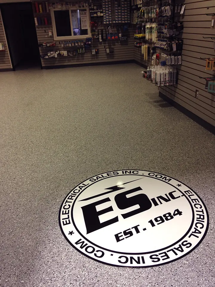 Retail sales floor in tan flake epoxy with a round logo inlay near the counter