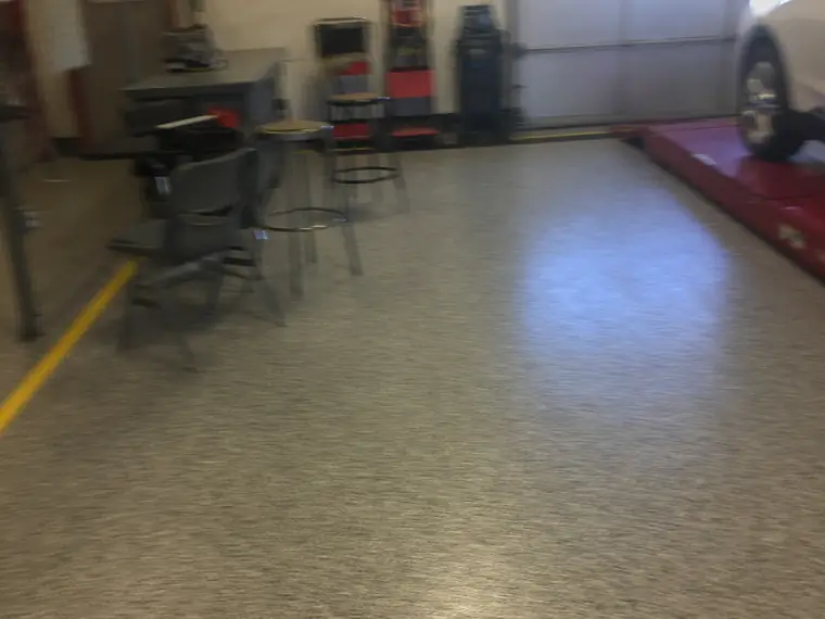 Olive flake epoxy floor in a vehicle service bay with a car on the lift