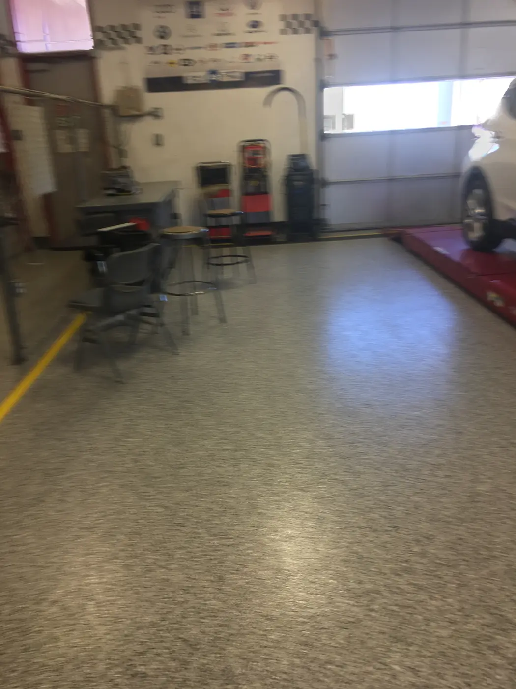 Olive flake epoxy floor in a vehicle service bay with a car on the lift
