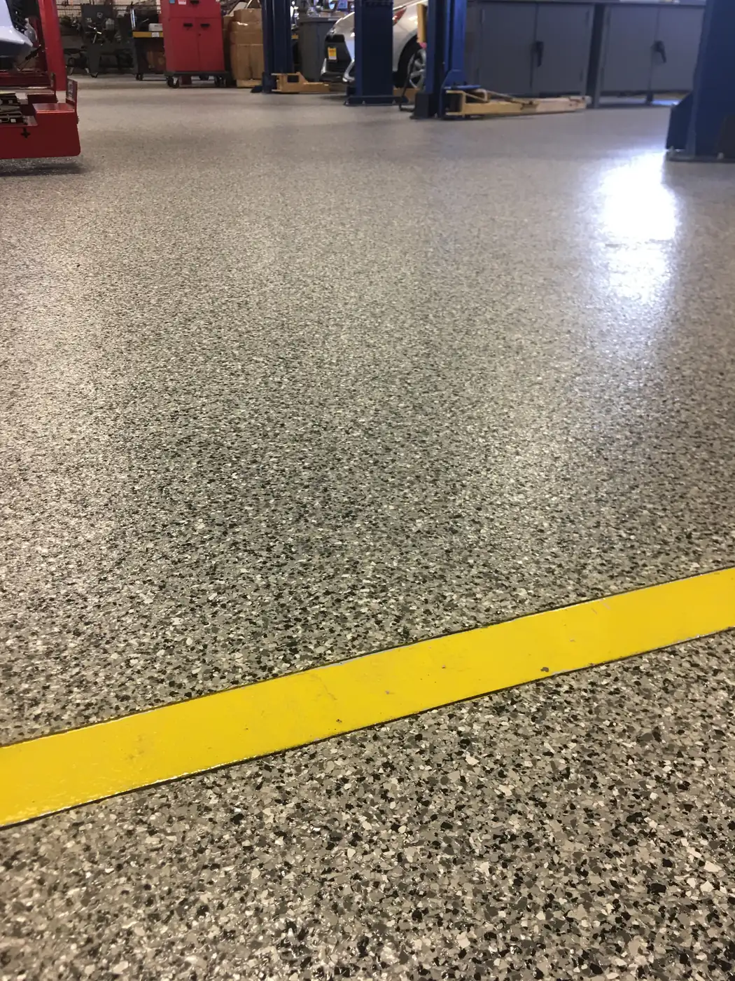 Gray flake epoxy floor with a yellow safety line running across it