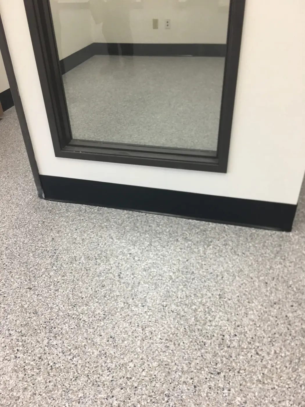 Gray flake epoxy floor meeting the base of a window display frame