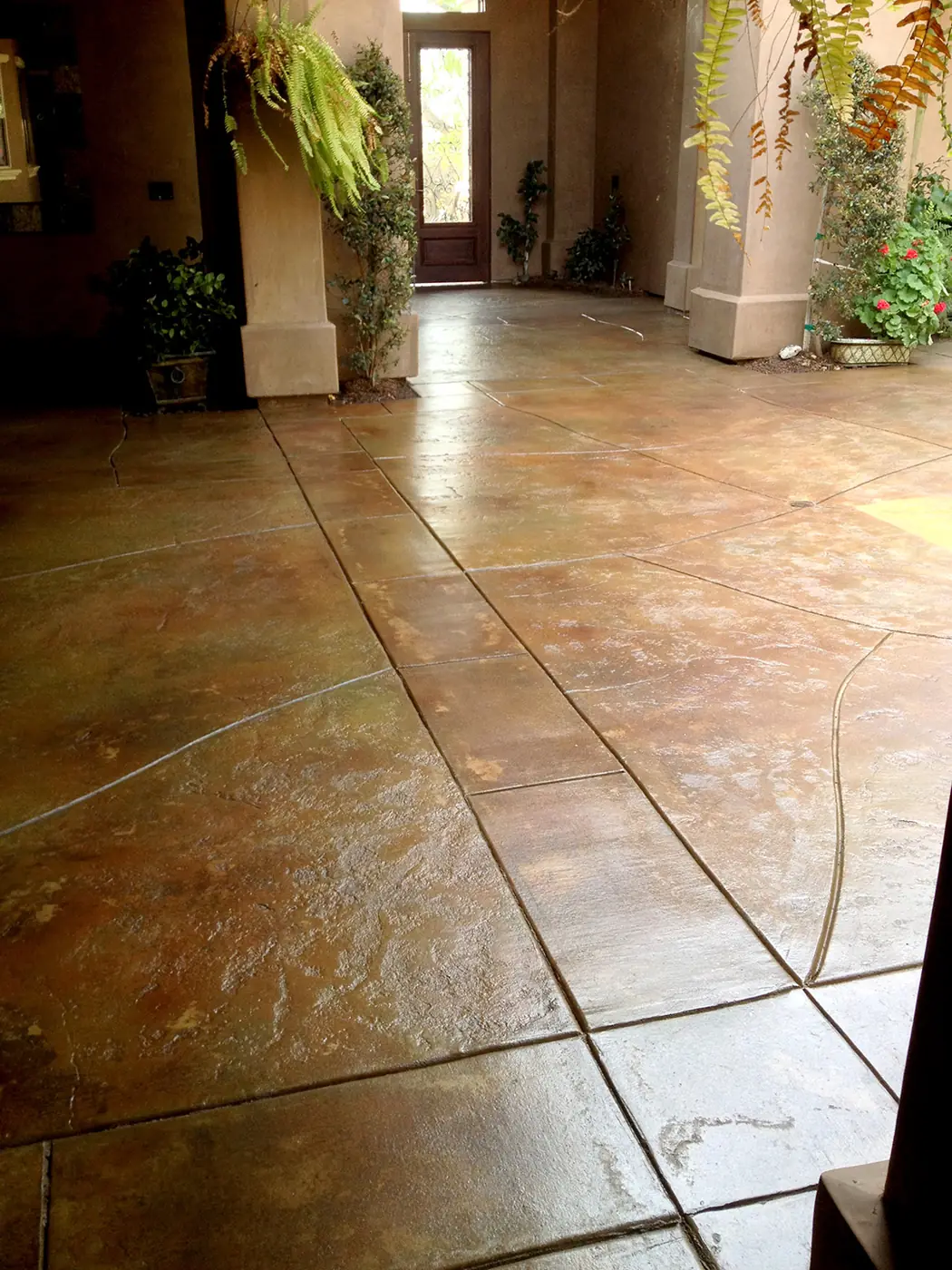 Stained entry patio scored in a tile pattern beside a stucco column