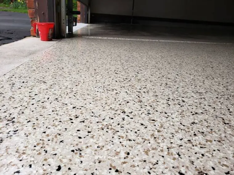 Cream, tan and black flake epoxy garage floor running out through the open door to the driveway