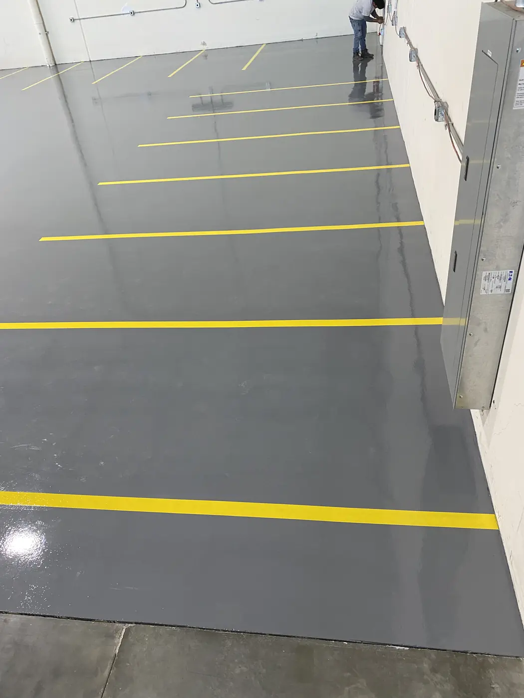 Yellow aisle lines running across a glossy gray epoxy warehouse floor
