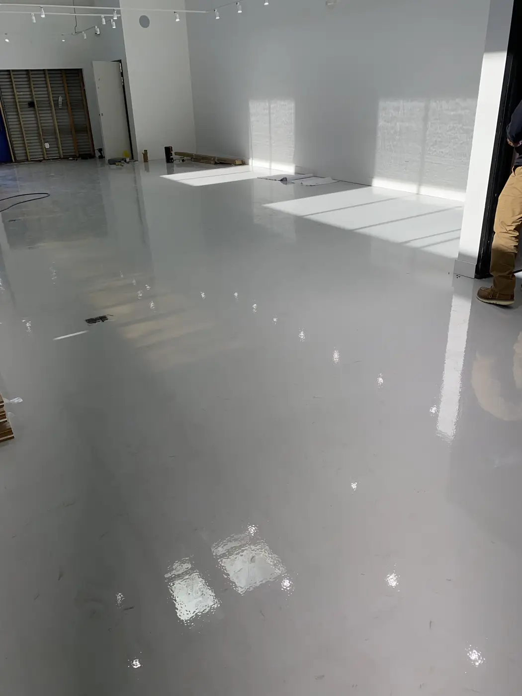 Gray epoxy floor in a bright industrial room with sunlight across it