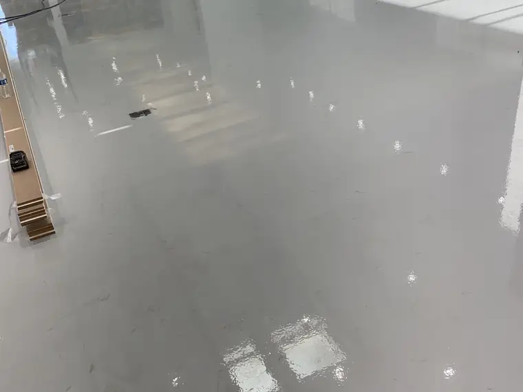 Glossy gray epoxy floor reflecting a row of high windows