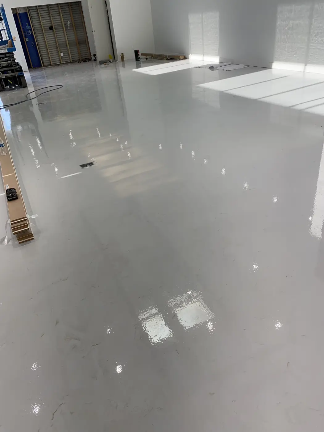 Glossy gray epoxy floor reflecting a row of high windows
