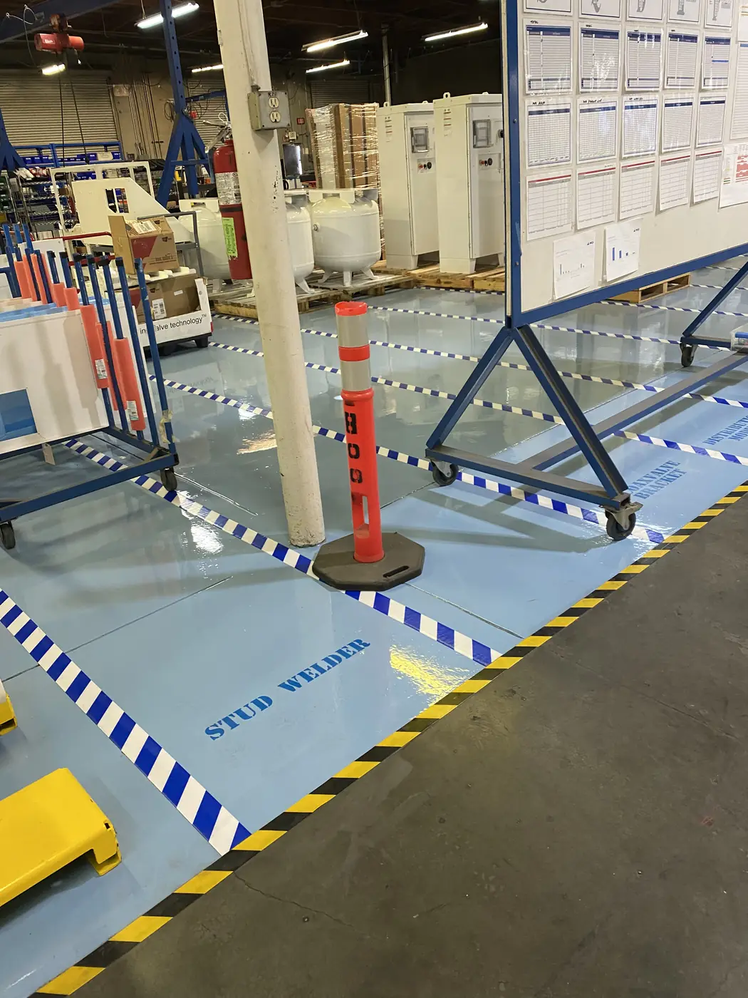 Blue and white striped safety zones marked on a pale blue epoxy plant floor