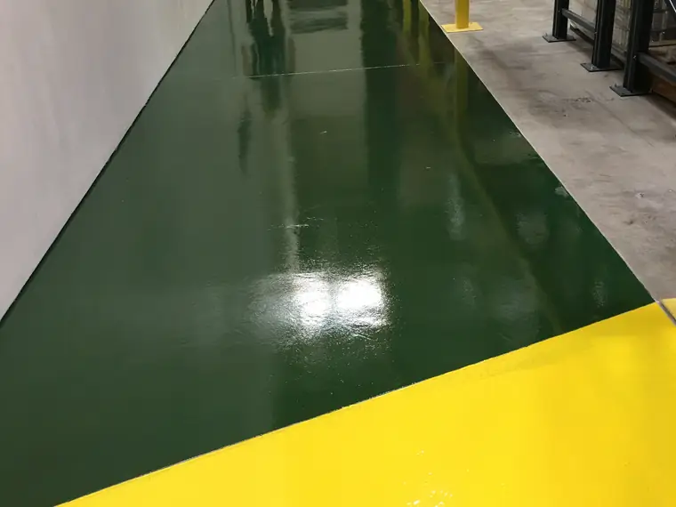 Dark green and yellow epoxy walkway cutting across a warehouse floor