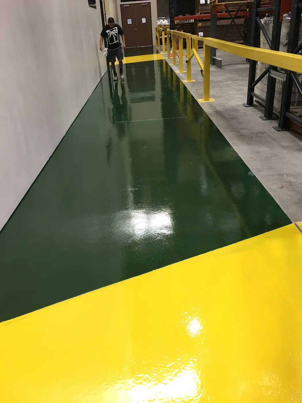 Dark green and yellow epoxy walkway cutting across a warehouse floor