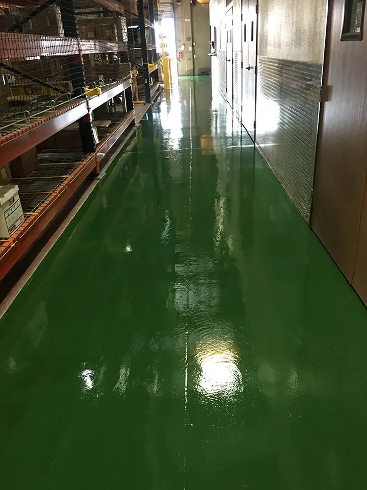 Green epoxy aisle running between tall warehouse racking
