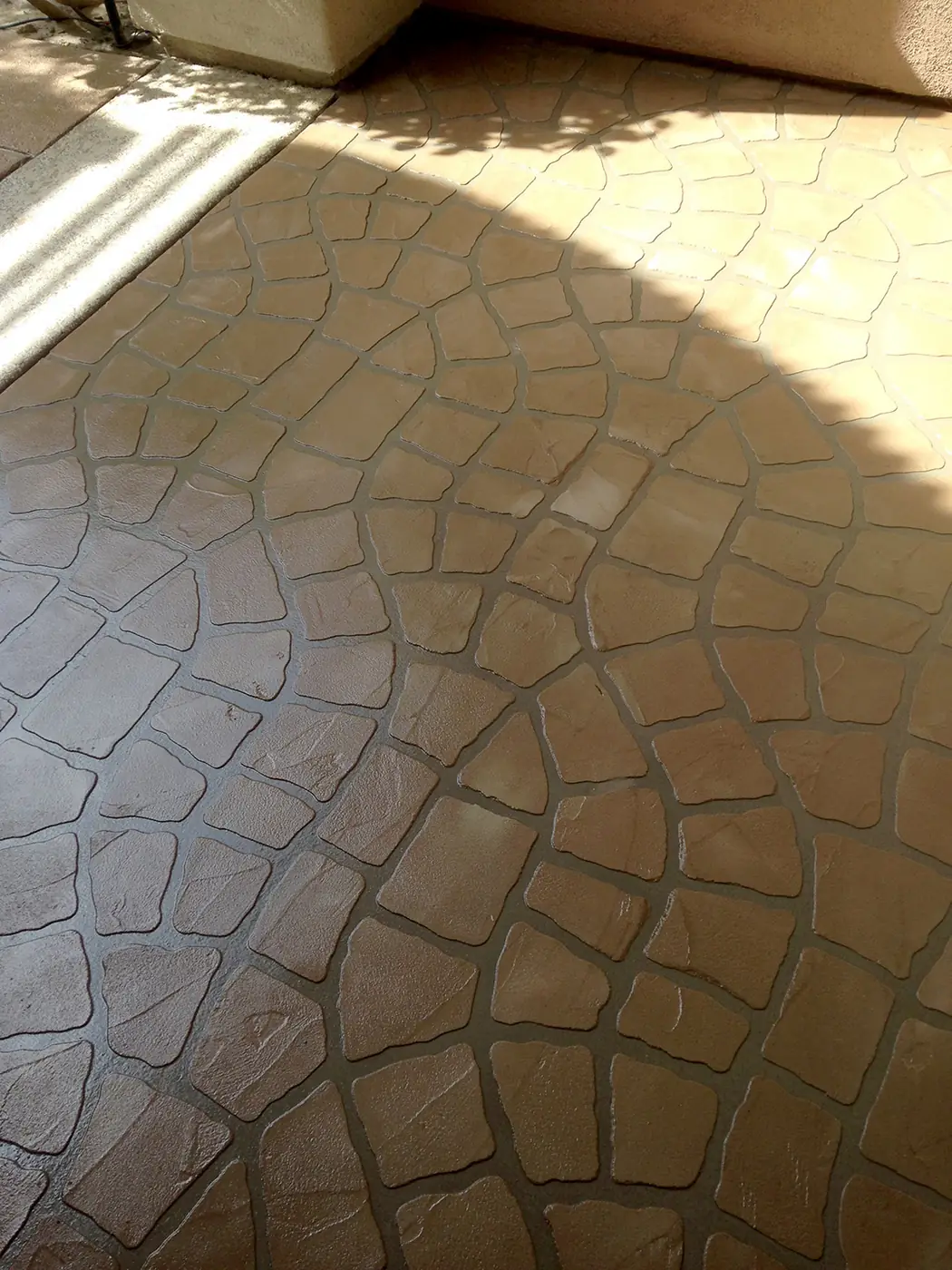 Cobblestone-pattern overlay stamped into a patio in warm brown