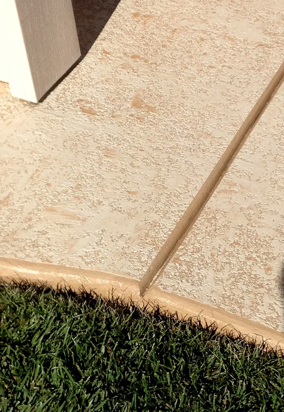 Light tan microtopping meeting a lawn edge with a contrasting border