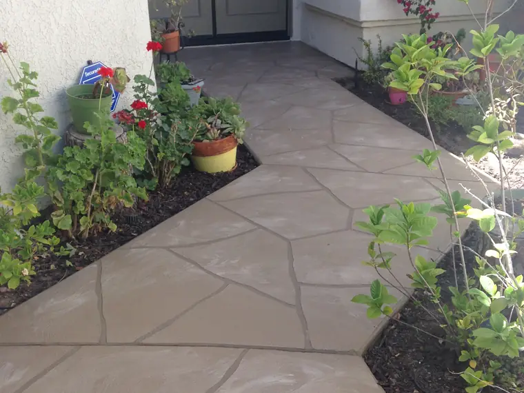 Flagstone-pattern overlay on an entry patio with planted borders