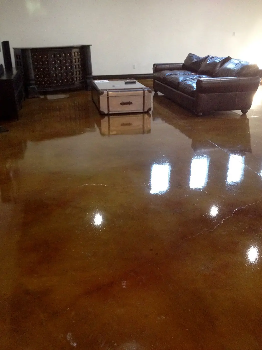 High-gloss copper stained concrete floor in a living room with leather seating