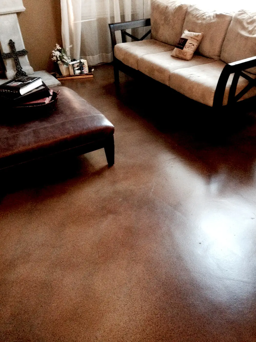 Brown stained concrete living room floor with a leather ottoman