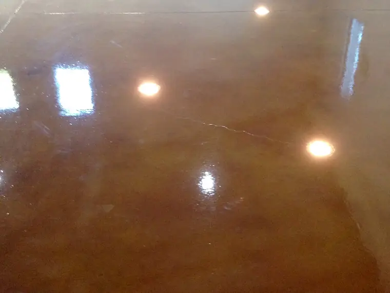 Glossy brown stained concrete floor reflecting ceiling downlights