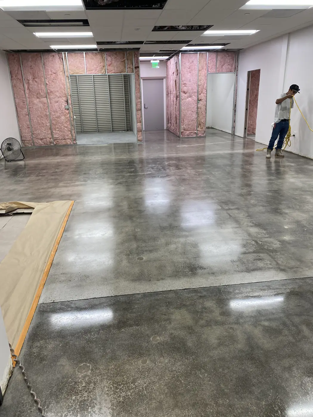 Worker crossing a freshly polished concrete floor in a partly built room