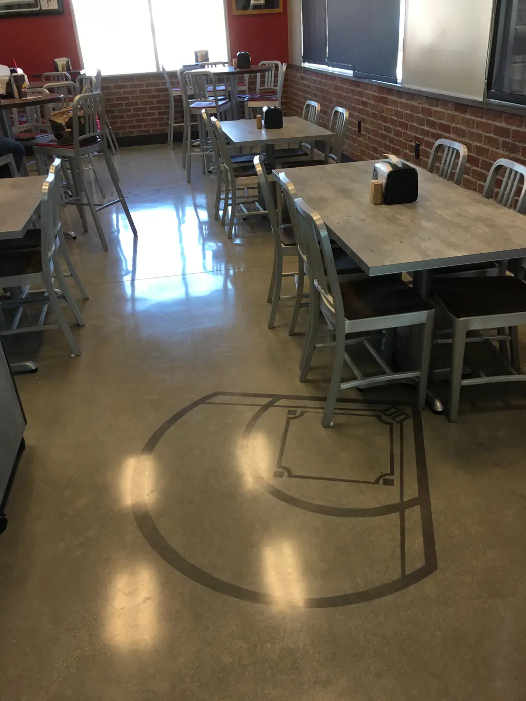 Polished concrete cafeteria floor with saw-cut graphics beneath the tables