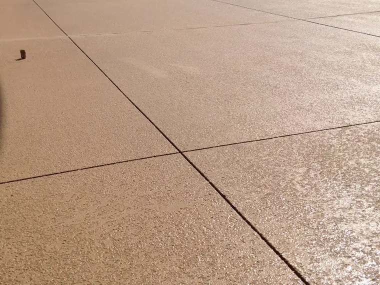 Wide tan textured pool deck running to the water's edge