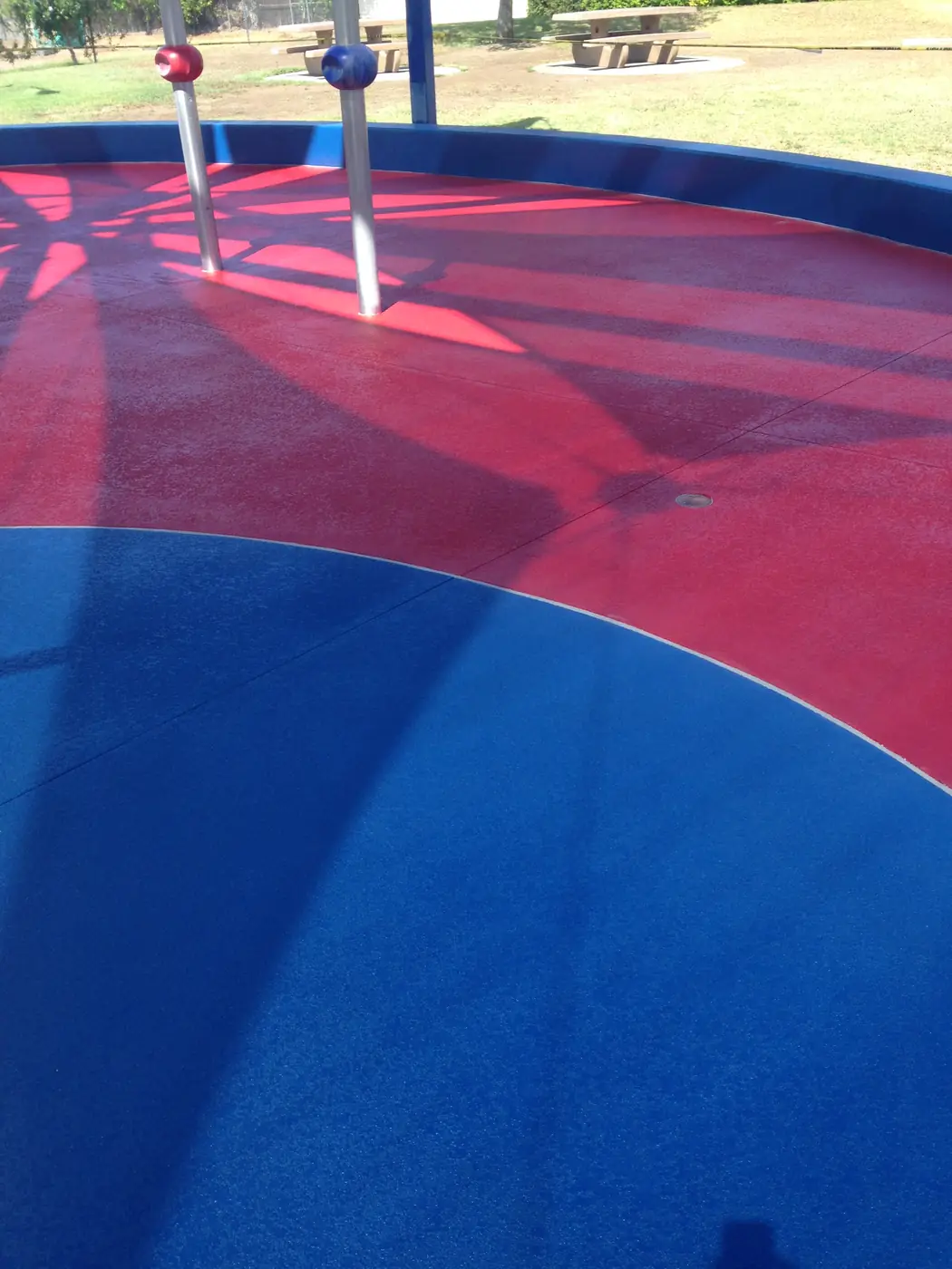 Red and blue curved splash pad coating around stainless play posts