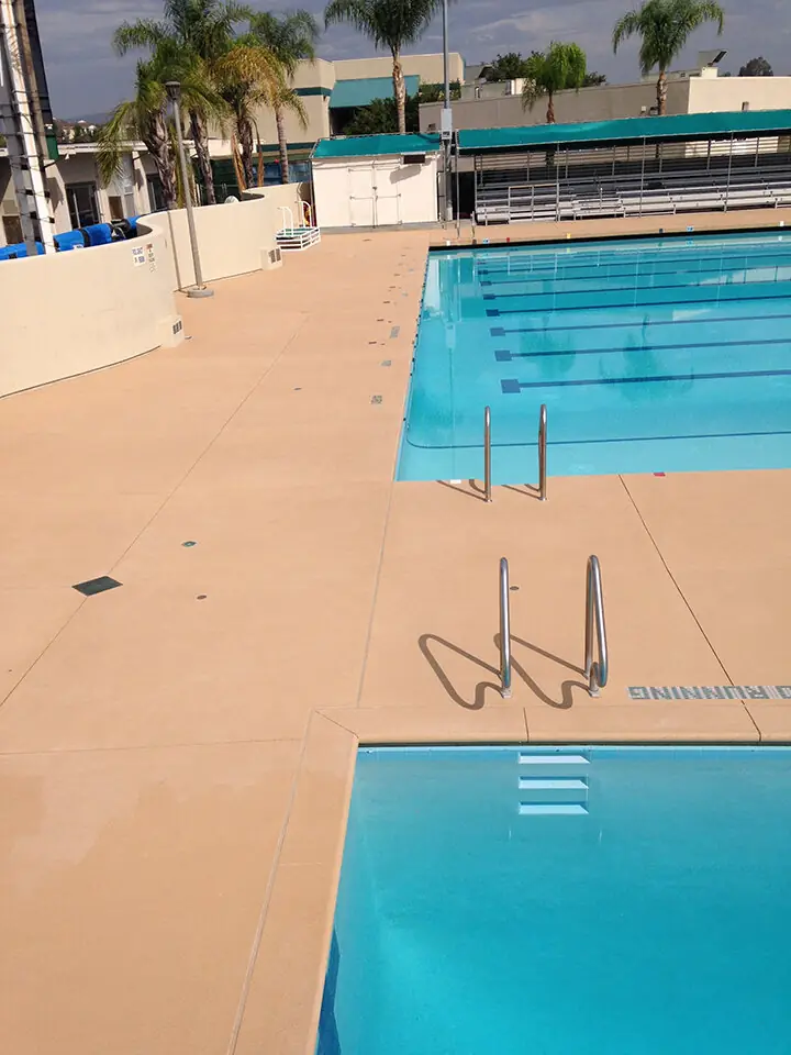 Tan textured deck around a commercial lap pool