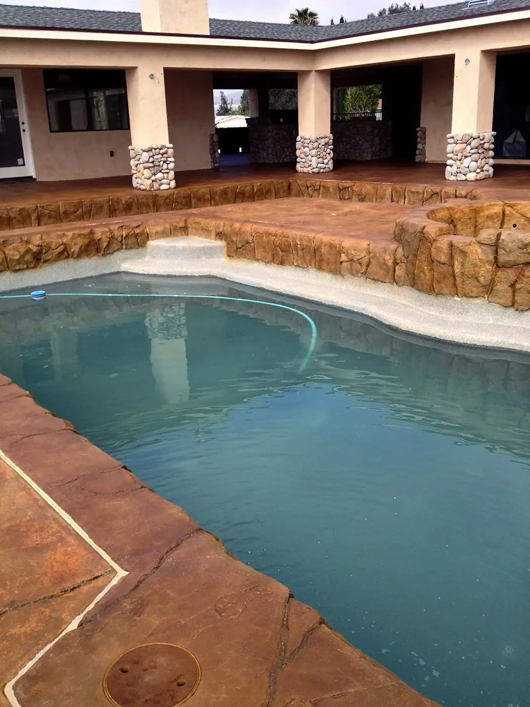Stained pool deck and rock coping around a freeform pool