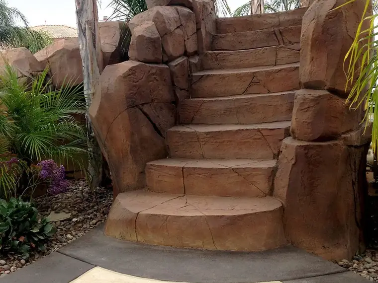 Restained rock staircase leading up beside a pool