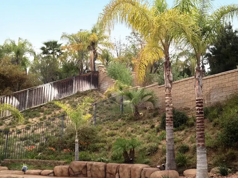 Restained rock retaining wall stepping up a planted hillside
