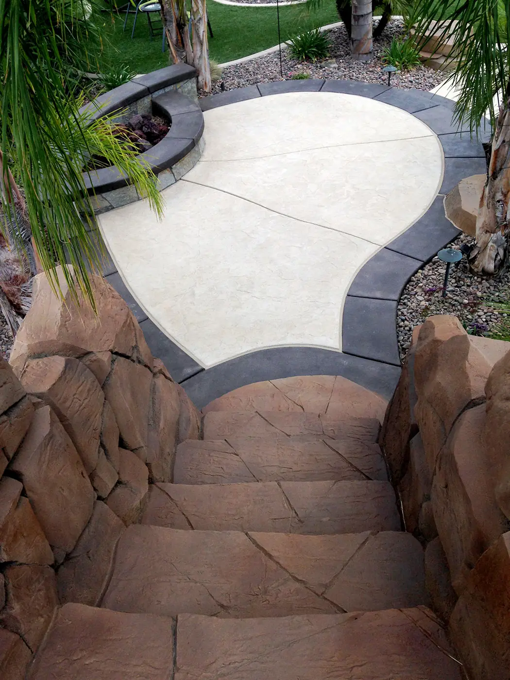 Restained rock steps leading up to a pale patio pad